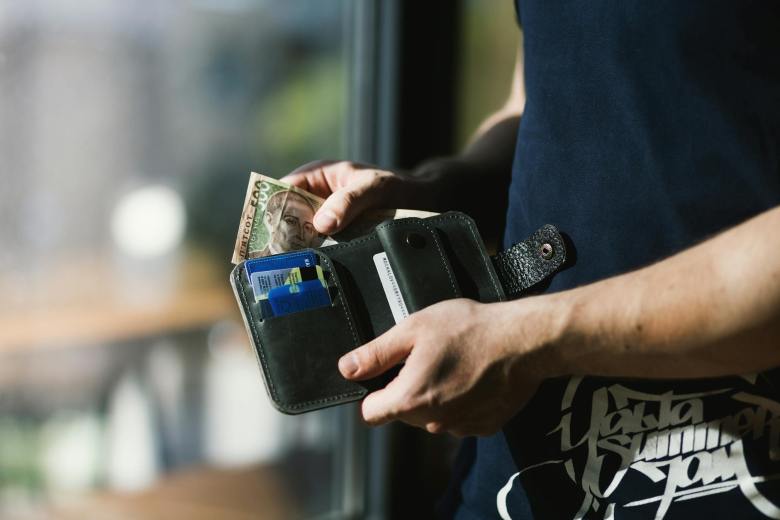 photograph of person holding black leather wallet with money Kenya faces economic strain with layoffs and cash flow issues; resilience, skill-building, cost optimization, and government support are key to recovery. Kenya Proposes New 15% Tax on Social Media and Online Businesses