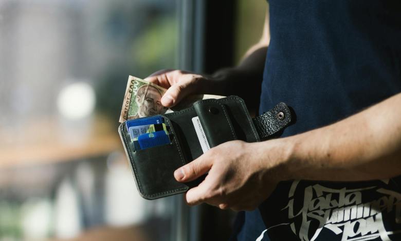 photograph of person holding black leather wallet with money Kenya faces economic strain with layoffs and cash flow issues; resilience, skill-building, cost optimization, and government support are key to recovery.